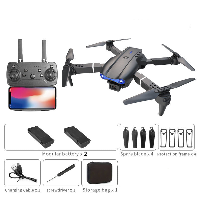 Black dual camera drone with remote control, accessories, and packaging on a white background.