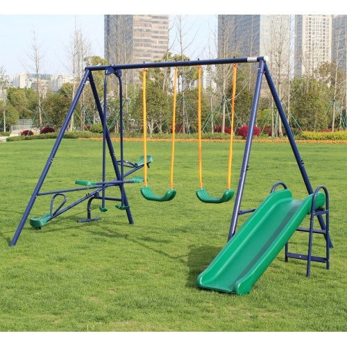 Children's playground set with swings and slide on grass, tall buildings in the background
